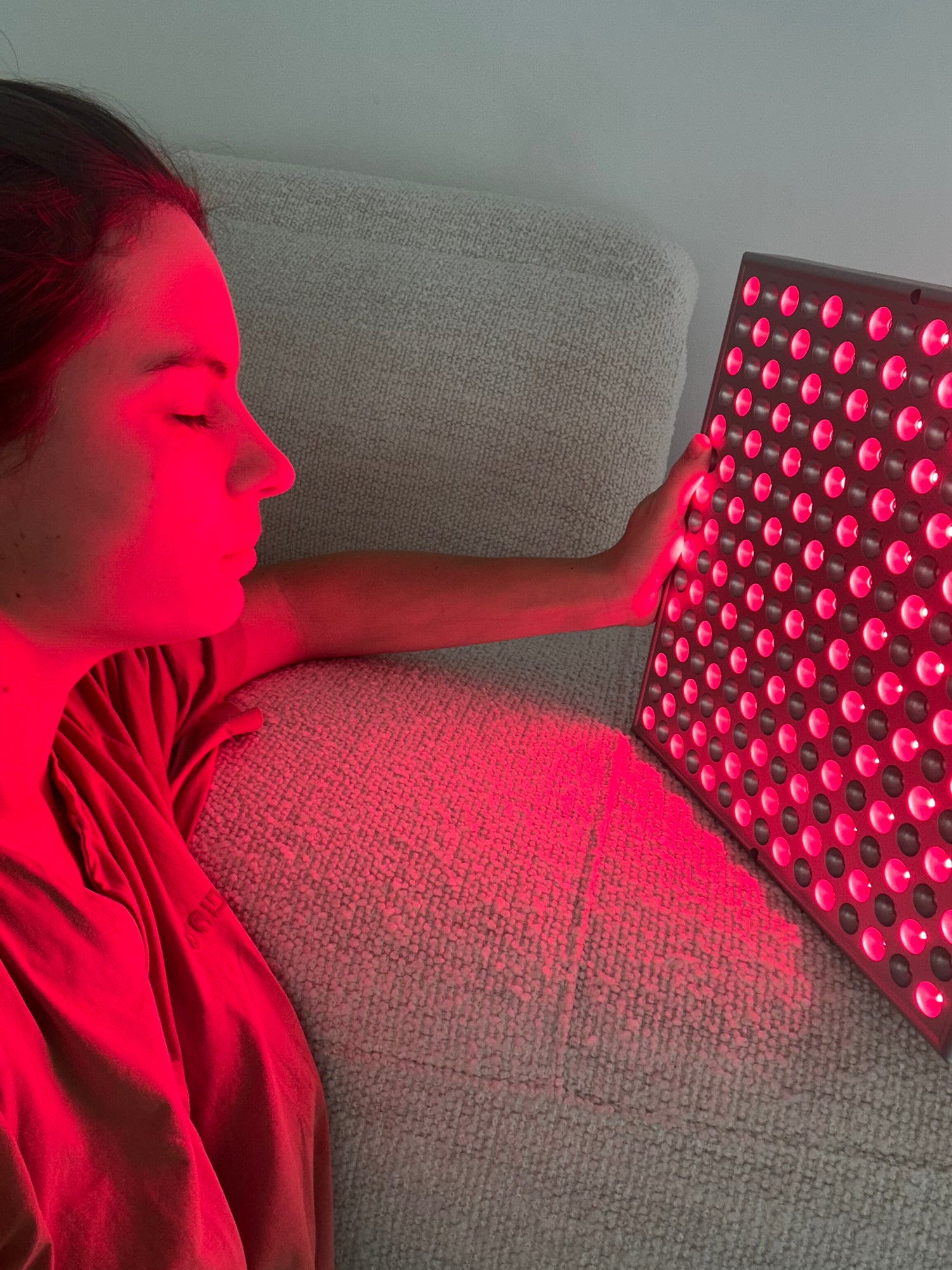 Woman using red light therapy device.