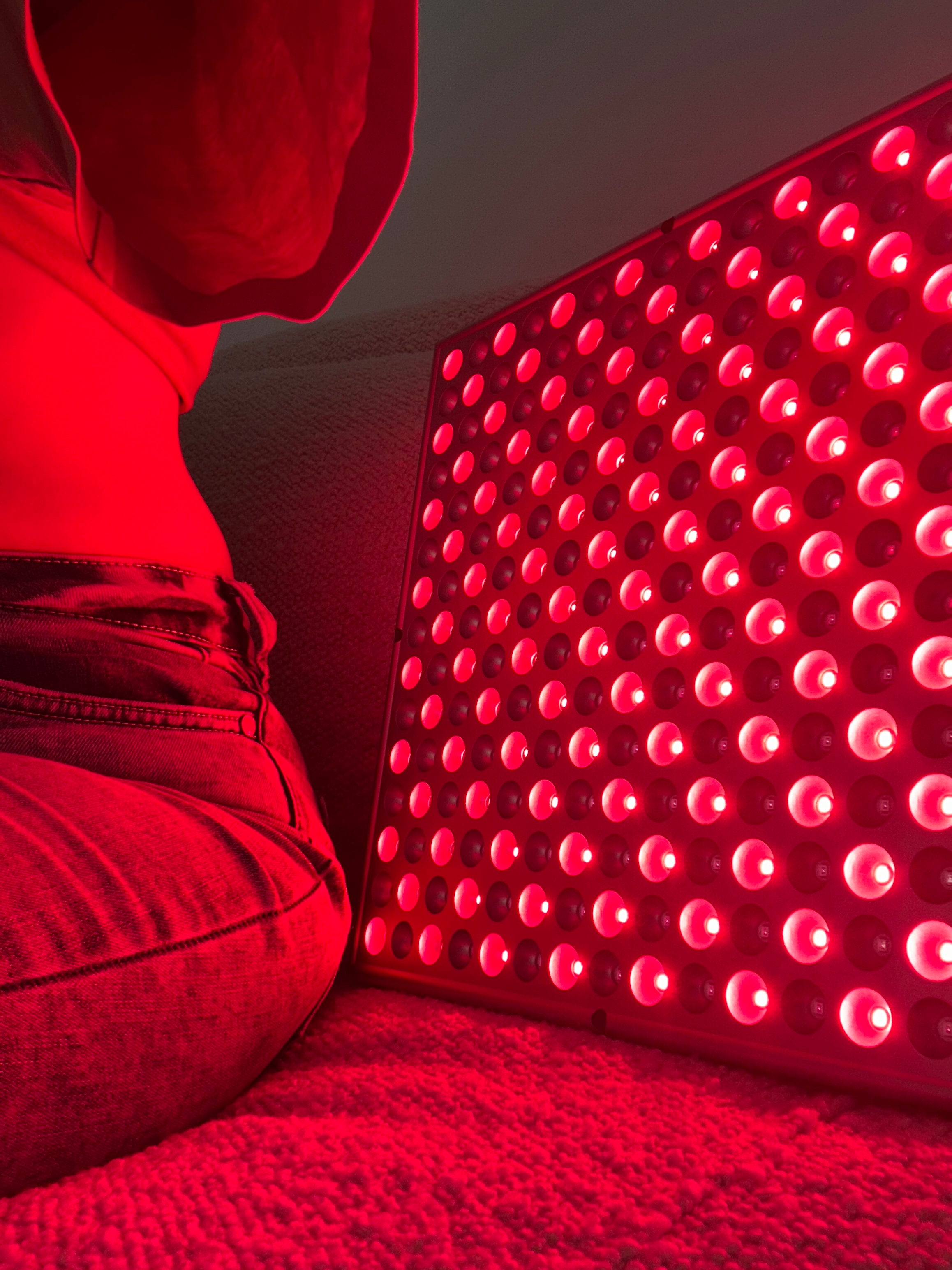 Person next to a red light therapy panel.